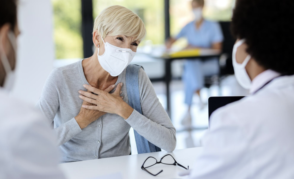 patient plaçant ses mains sur sa poitrine pour suggérer une douleur cardiaque